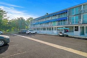 A multi-story hotel with balconies, a parking area, and a golf cart. - Beachside Villa Dorado Pool Beach Access (Dorado)