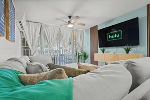 Una sala de estar moderna con un sofá, un televisor de pantalla plana y un ventilador de techo.