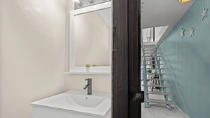 A bathroom with a white sink, a mirror, and a dark wooden door.