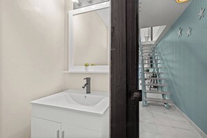 A bathroom with a white sink, a mirror, and a dark wooden door. - Beachside Villa Dorado Pool Beach Access (Dorado)