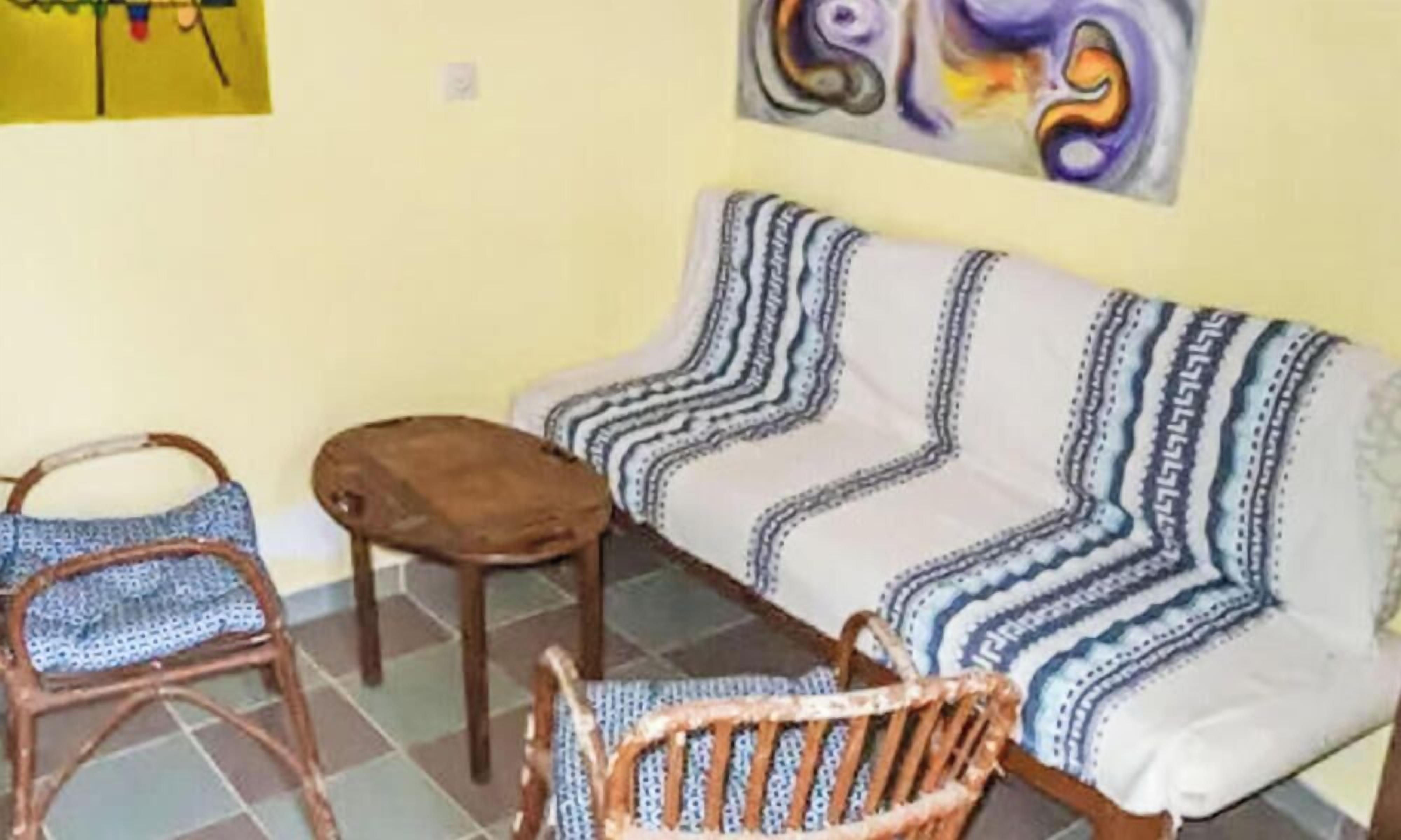 Una habitación con un sofá, dos sillas, un taburete pequeño y un cuadro en la pared.