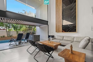 Ein modernes Wohnzimmer mit Pool, einer Couch, einem Couchtisch und einem großen abstrakten Gemälde.