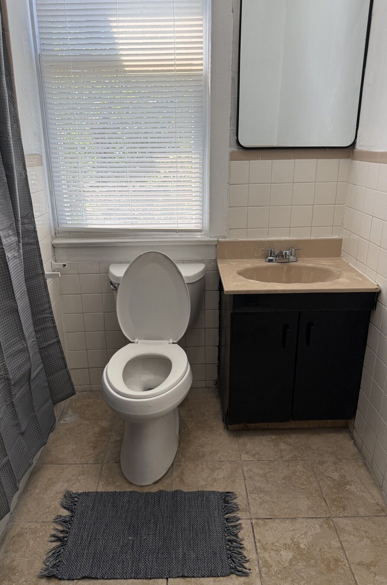 A bathroom with a toilet, sink, and window.