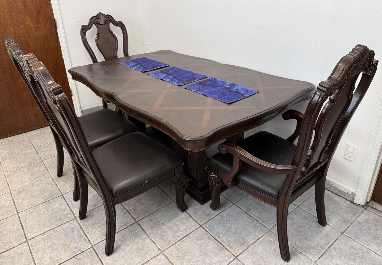 A dining table with four chairs, a tiled floor, and a door in the background.