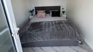 A bedroom with a bed, a painting, bedside tables, and a door. - Equi Lodge: A Horse-Loving Retreat Near Disney (La Houssaye-en-Brie)