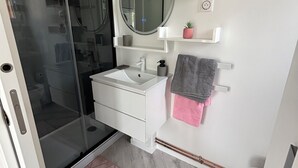 A bathroom with a glass shower enclosure, a white sink, a mirror, and a towel rack. - Equi Lodge: A Horse-Loving Retreat Near Disney (La Houssaye-en-Brie)