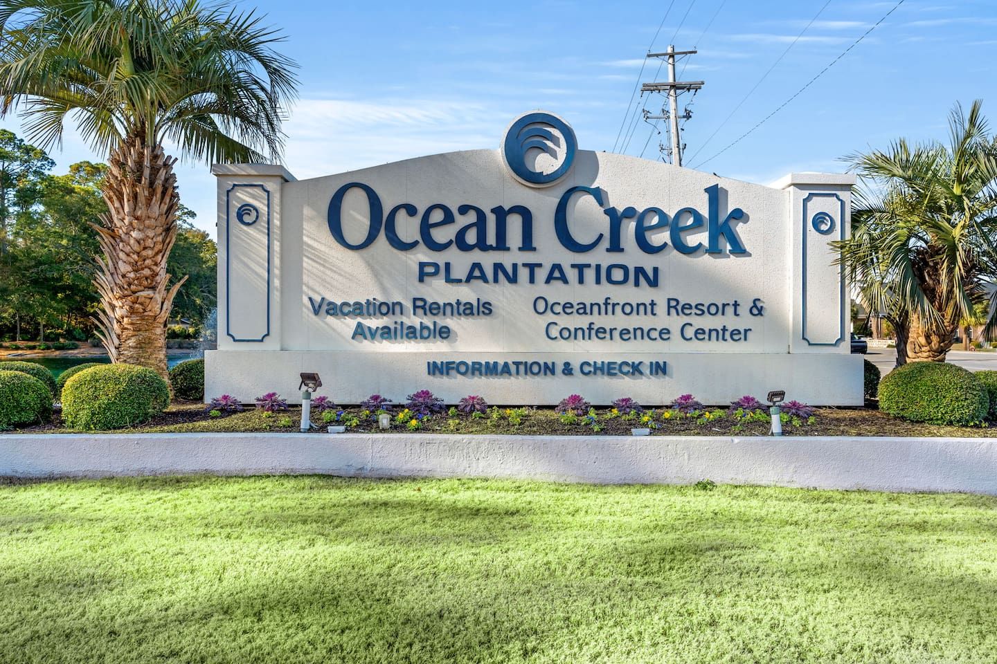 A sign for Ocean Creek Plantation with a logo, indicating vacation rentals, a resort, and a conference center.