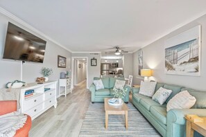 A modern living room with a sofa, coffee table, and a flat-screen TV. - Ocean Creek Lodge 4 2276 - Beach, Pools, Hot Tubs (Myrtle Beach)
