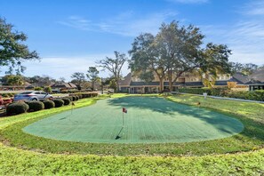 Ein Golfplatz mit Putting Green, umgeben von gepflegten Hecken und Bäumen.
