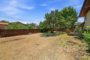 A backyard with a wooden fence, a tree, and a house. - Peaceful 4-bedroom house with AC in Colorado Springs (Colorado Springs)