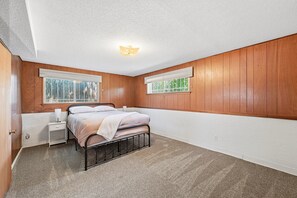 A bedroom with a bed, nightstand, and two windows with blinds. - Peaceful 4-bedroom house with AC in Colorado Springs (Colorado Springs)