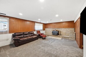 A room with a leather sofa, a recliner, a stone fireplace, and a television. - Peaceful 4-bedroom house with AC in Colorado Springs (Colorado Springs)