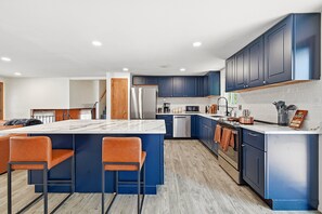 A modern kitchen with blue cabinets, a central island with bar stools, stainless steel appliances, and a visible WiFi sign. - Peaceful 4-bedroom house with AC in Colorado Springs (Colorado Springs)