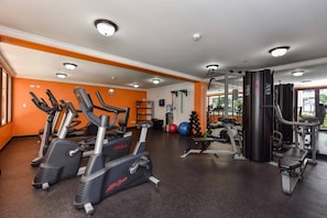 Ein Fitnessstudio mit Laufbändern, Kraftgeräten und Kurzhanteln.