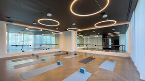 Ein geräumiger Yoga-Raum mit Holzböden, mehreren Yogamatten und Spiegelwänden.