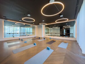 Ein geräumiger Yoga-Raum mit Holzböden, mehreren Yogamatten und Spiegelwänden.