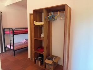A bunk bed with a wooden wardrobe beside it, containing a kettle, a red tray, and a box labeled 'CLOROX'.