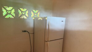 A white refrigerator with a power cord plugged in, a wall socket, and decorative window patterns. - Ocean view, with pool ,block to beach , , Cozy 1-room house in bucaro with AC (Tonosí)
