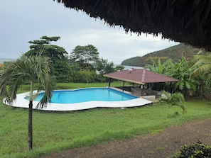 A swimming pool with a surrounding grassy area and a structure with a red roof.