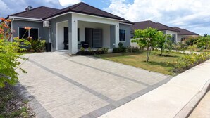 A residential property with a paved driveway, a covered porch, and a well-maintained lawn. - DraxHall~3BR~Poo ~Beach Access - 24hr Security (St. Ann's Bay)