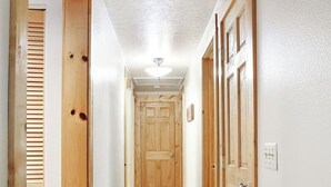Un couloir étroit avec des portes en bois et un luminaire au plafond.