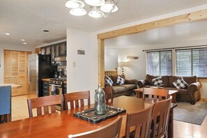 A kitchen with a refrigerator, stove, and dining area with chairs and a table. - Mountain Getaway • Hot Tub • Game Room • Sleeps 10 • Minutes to Payette Lake (McCall)
