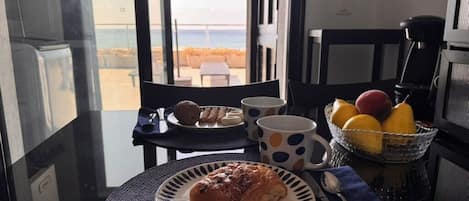 A breakfast setting with a croissant on a plate, a bowl of fruit, and a coffee machine.