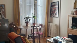 Ein Wohnzimmer mit Esstisch, Stühlen, einer Couch, einem Couchtisch und einer Heizung.