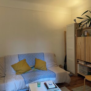 A small, cozy room with a single bed, a bedside table with a book and a glass, and a wooden wardrobe. - Fully Equipped Apartment in La Bastille (Paris)