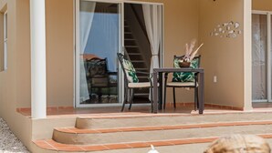 Uma varanda com mesa e cadeiras, uma escadaria e um muro decorado com motivos de peixe.