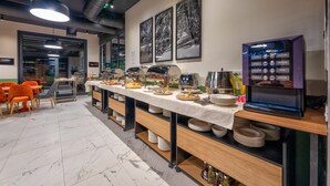 Een buffetopstelling met diverse gerechten, een koffieapparaat en zitplaatsen.