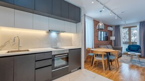 A modern kitchen with a marble countertop, integrated oven, and dark cabinetry.