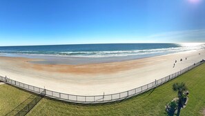 Una spiaggia con una passeggiata a forma di curva e una zona recintata.