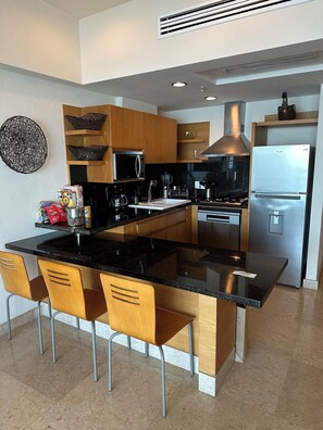 A modern kitchen with a central island, wooden cabinets, stainless steel appliances, and a black countertop. - Resort with 2 bedrooms and AC in serene Puerto Vallarta - sleeps 6 (Puerto Vallarta)