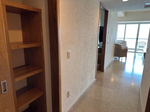 A hallway with wooden shelving units, a textured wall, and a glimpse of a room with a wicker chair and a bed. - Resort with 2 bedrooms and AC in serene Puerto Vallarta - sleeps 6 (Puerto Vallarta)