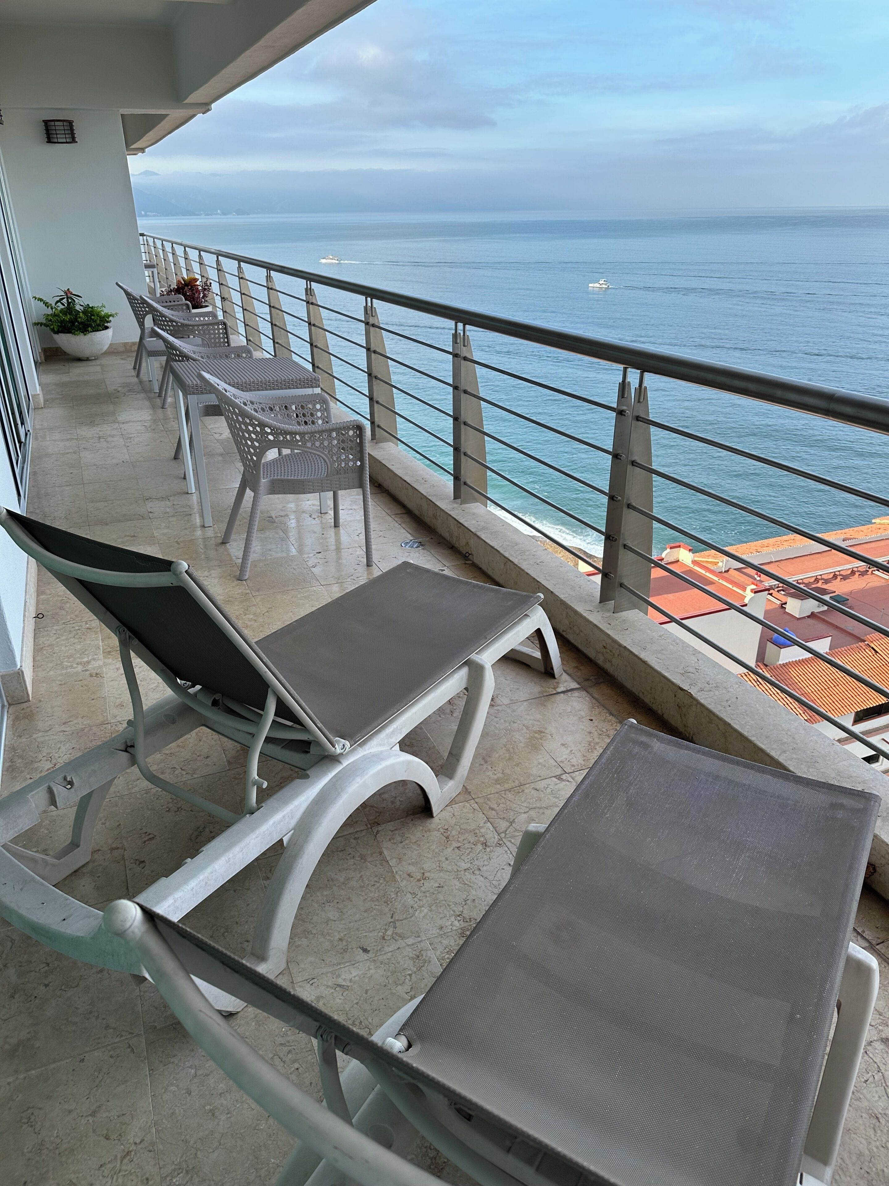 Ein Balkon mit Metallstühlen und -tischen mit Blick auf das Meer.