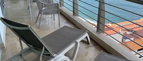 Ein Balkon mit Metallstühlen und -tischen mit Blick auf das Meer.