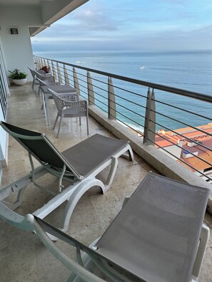 A balcony with metal chairs and tables, overlooking the sea. - Resort with 2 bedrooms and AC in serene Puerto Vallarta - sleeps 6 (Puerto Vallarta)