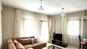 A living room with a sofa, a coffee table, a TV, and curtains.