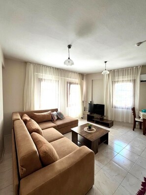 A living room with a sofa, a coffee table, a TV, and curtains.
