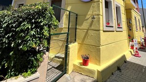 A two-story building with a yellow facade and a red roof. There is a sign on the front that reads 'ASYA ASIL APART'.