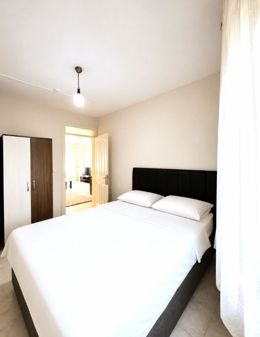 Une chambre à coucher avec un grand lit, une armoire et une porte donnant sur une autre pièce.