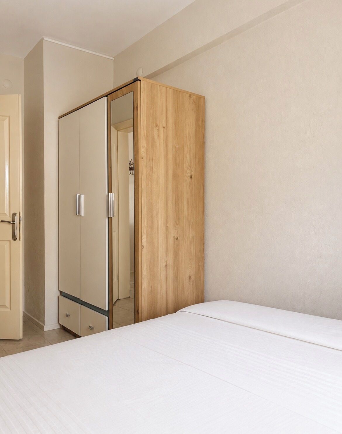 A bedroom with a bed, a wardrobe, and a door.