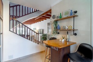 Eine Treppe mit hölzernen Geländern, eine Holztresen mit Hockern und ein wandmontiertes Regal mit Dekoration.