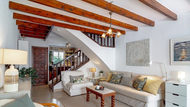 A spacious living room with a staircase, a sofa set, a coffee table, and a side table with a lamp. - Holiday Home in Nerja With Sea Views & Pool (Nerja)