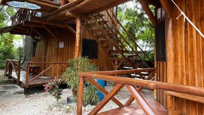 Un rustico chalet in legno con una scala in legno, un cartello che indica un'area tranquilla e un piccolo spazio salotto esterno.