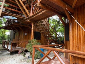 Eine rustikale Holzblockhütte mit einer Holztreppe, einem Schild, das für eine ruhige Zone wirbt, und einer kleinen Außen-Sitzgelegenheit.