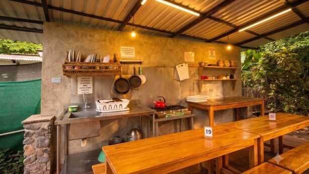 A rustic outdoor kitchen with a stone sink, wooden tables, and a gas stove.