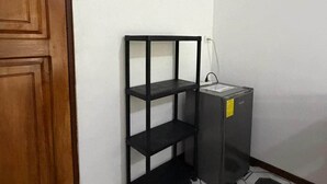 A corner with a wooden door, a black metal shelf unit, and a small electrical box.