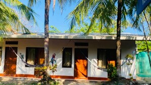 A two-story building with a porch, palm trees, and a hammock.